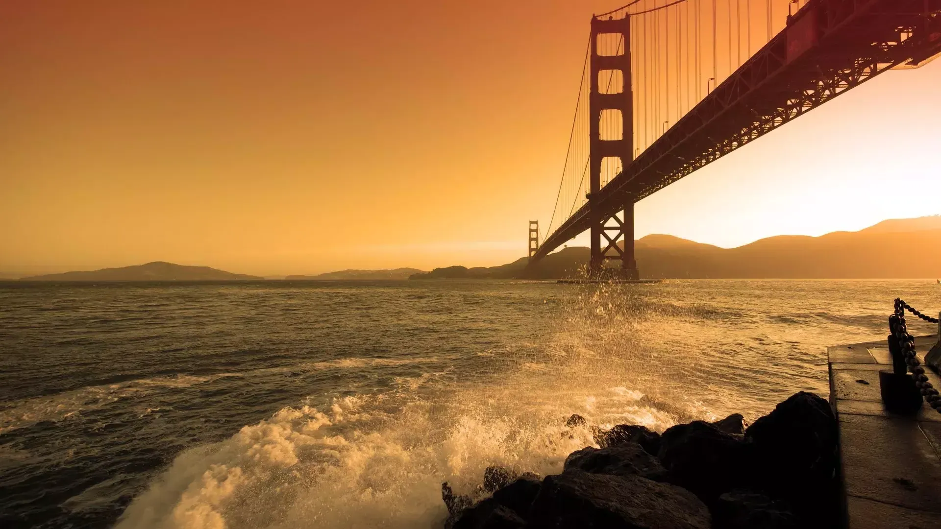 Bei sunset brechen die Wellen in der Nähe von Fort Point unter der Golden Gate Bridge .